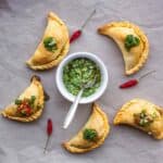 Empanadas de lentejas horneadas con chimichurri, servidas con ají picante y salsa verde.