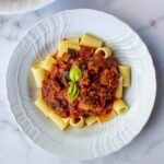 Pasta con salsa casera de tres ingredientes servida en plato blanco.