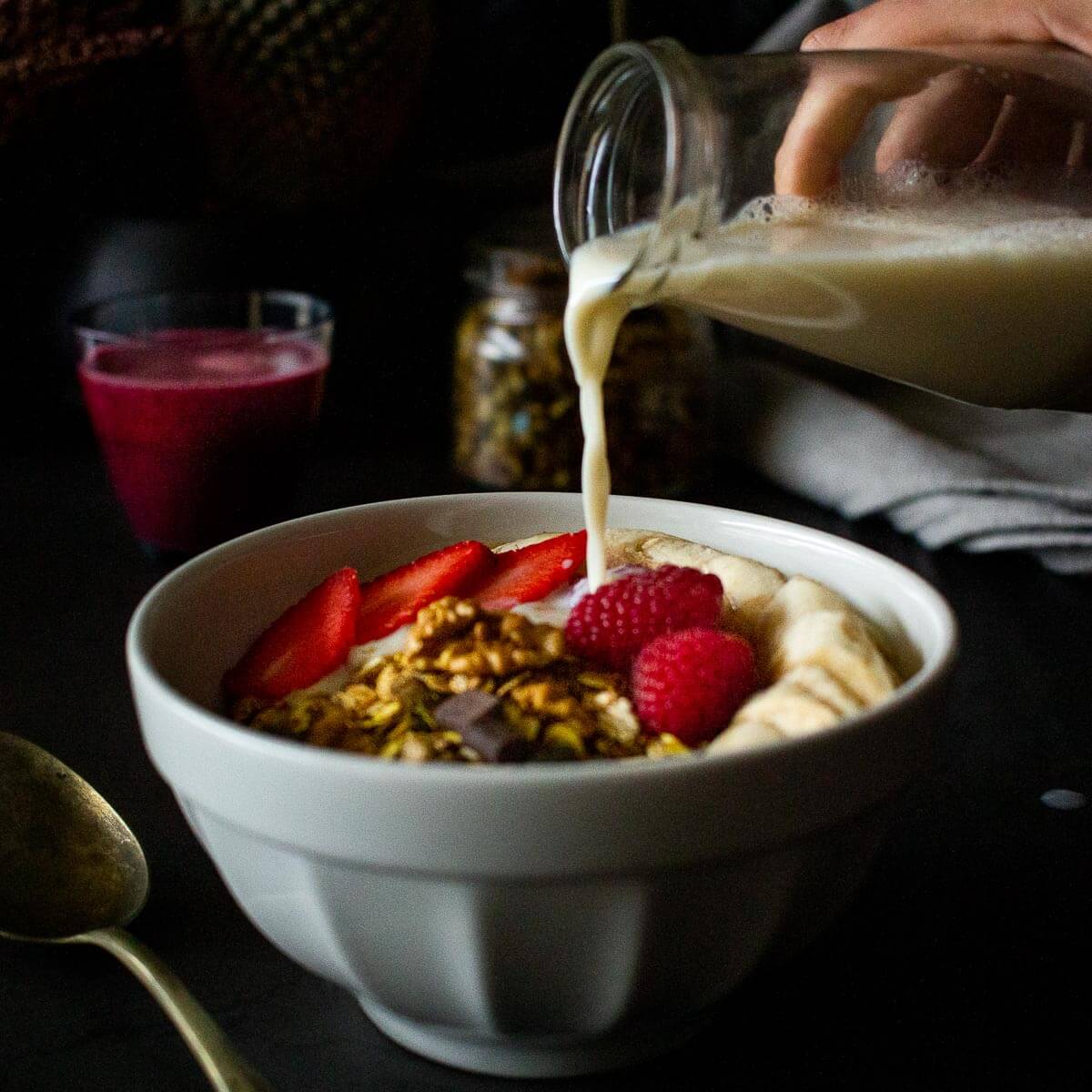 sirviendo leche vegetal sobre cazo con granola casera.