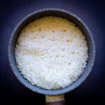 Arroz jazmín cocido en una olla pequeña con textura esponjosa.