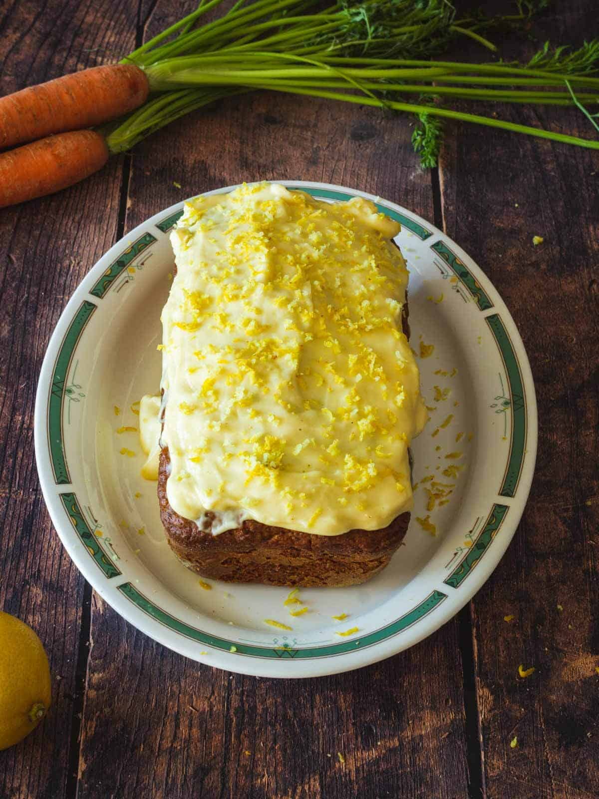 tarta de zanahoria terminada y presentada con glaseado y rayadura de cáscara de limón.