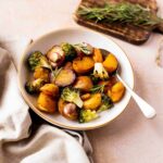 Patatas asadas crujientes servidas con brócoli Romanesco y hierbas frescas, perfectas como guarnición.