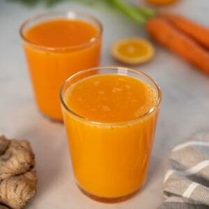 dos vasos jugo fresco de zanahoria, naranja y jengibre.