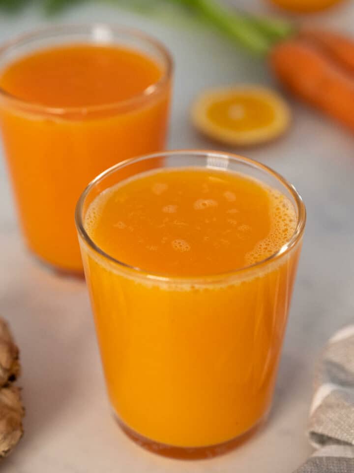 dos vasos jugo fresco de zanahoria, naranja y jengibre.