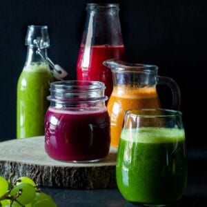 jarras y botellas de vidrio con jugos saludables para desayunar prensados en frío featured.