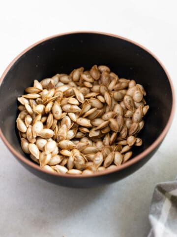 bowl con semillas de calabaza tostadas sobre la mesa featured.