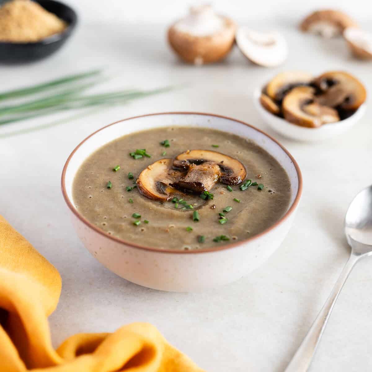 Crema de champiñones servida en un bowl junto a una cuchara.