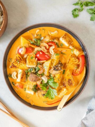 curry de verduras con leche de coco servido en un bowl sobre la mesa.