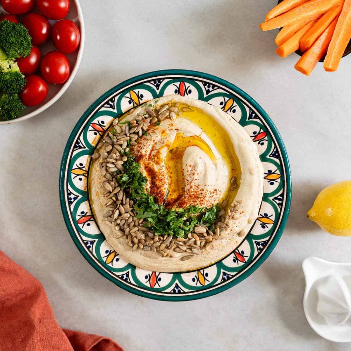 hummus de lentejas emplatado acompañado de un bol con tomates y otro con bastones de zanahoria.