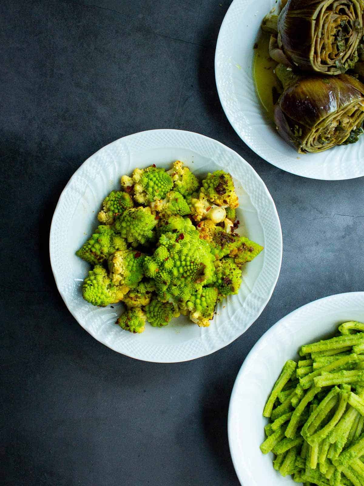 brócoli romanesco acompañado de alcachofas y judías verdes, servidos en platos diferentes.