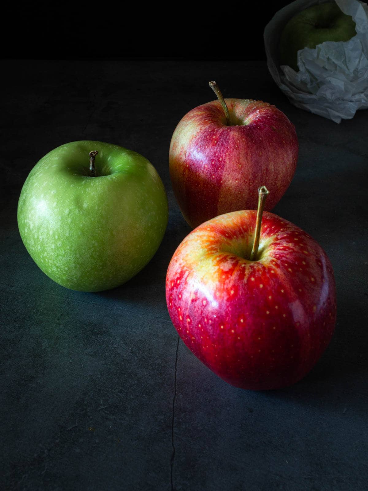una manzana verde junto a dos manzanas rojas gala.