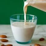 sirviendo leche de almendras en un vaso.