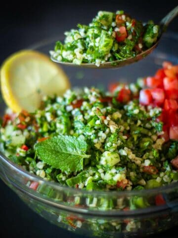 cucharada con ensalada tabule y un bowl servido de fondo.