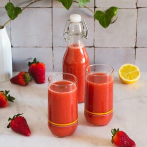 jugo de fresa servido en vasos y almacenado en una botella.