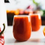 jugo de pimiento rojo y zanahoria servido en dos vasos de vidrio.