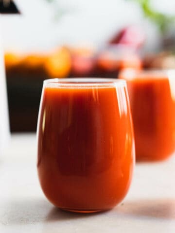 jugo de pimiento rojo y zanahoria servido en dos vasos de vidrio.