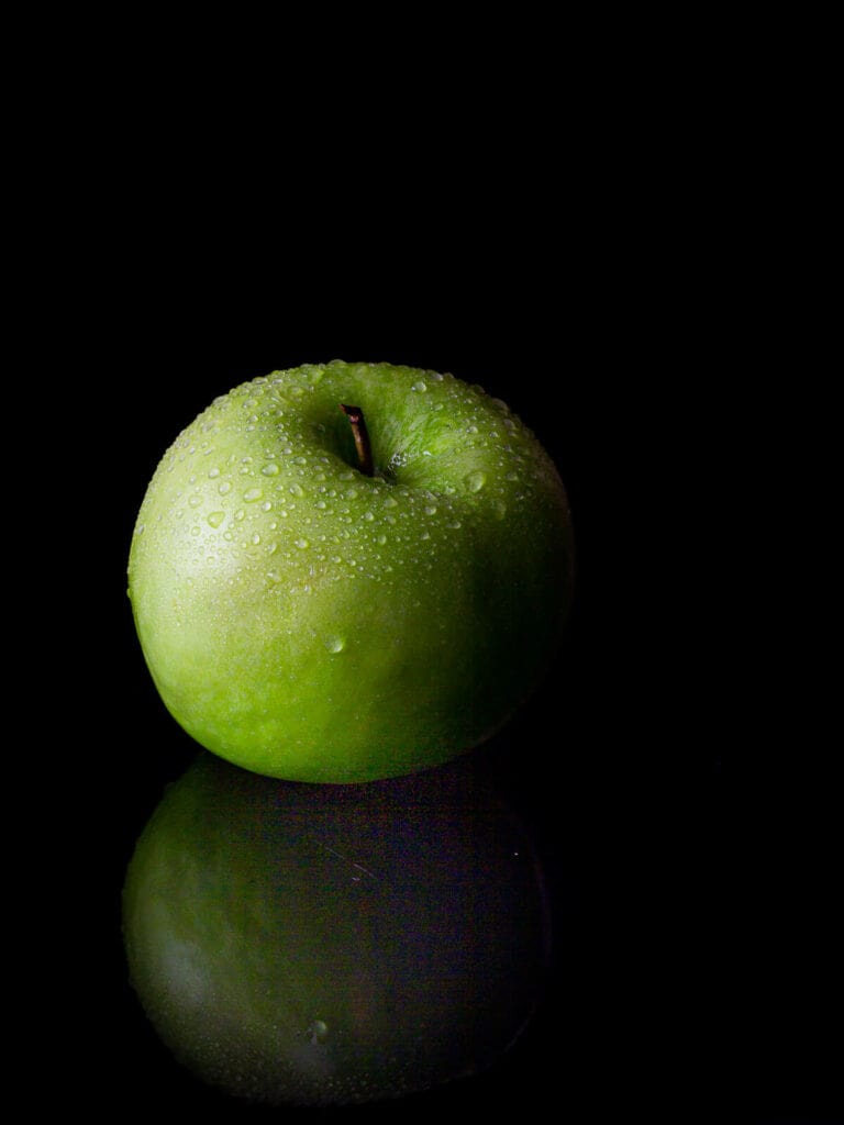 manzana verde sobre fondo negro.