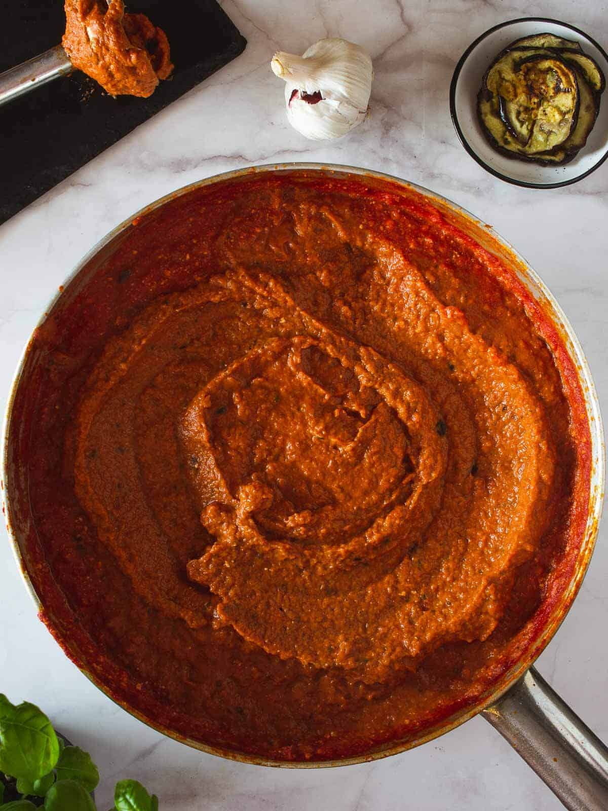 Salsa roja espesa hecha con salsa de tomate y ricotta mezclada con ricotta vegana y rodajas de berenjena asada.