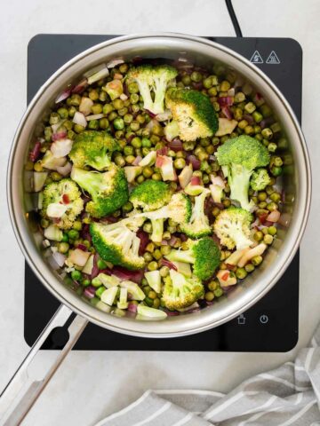 verter zumo de limón en una sartén caliente para desglasar y levantar los sabores del ajo salteado, las cebollas, los guisantes verdes y el brócoli, creando una mezcla fragante y colorida.