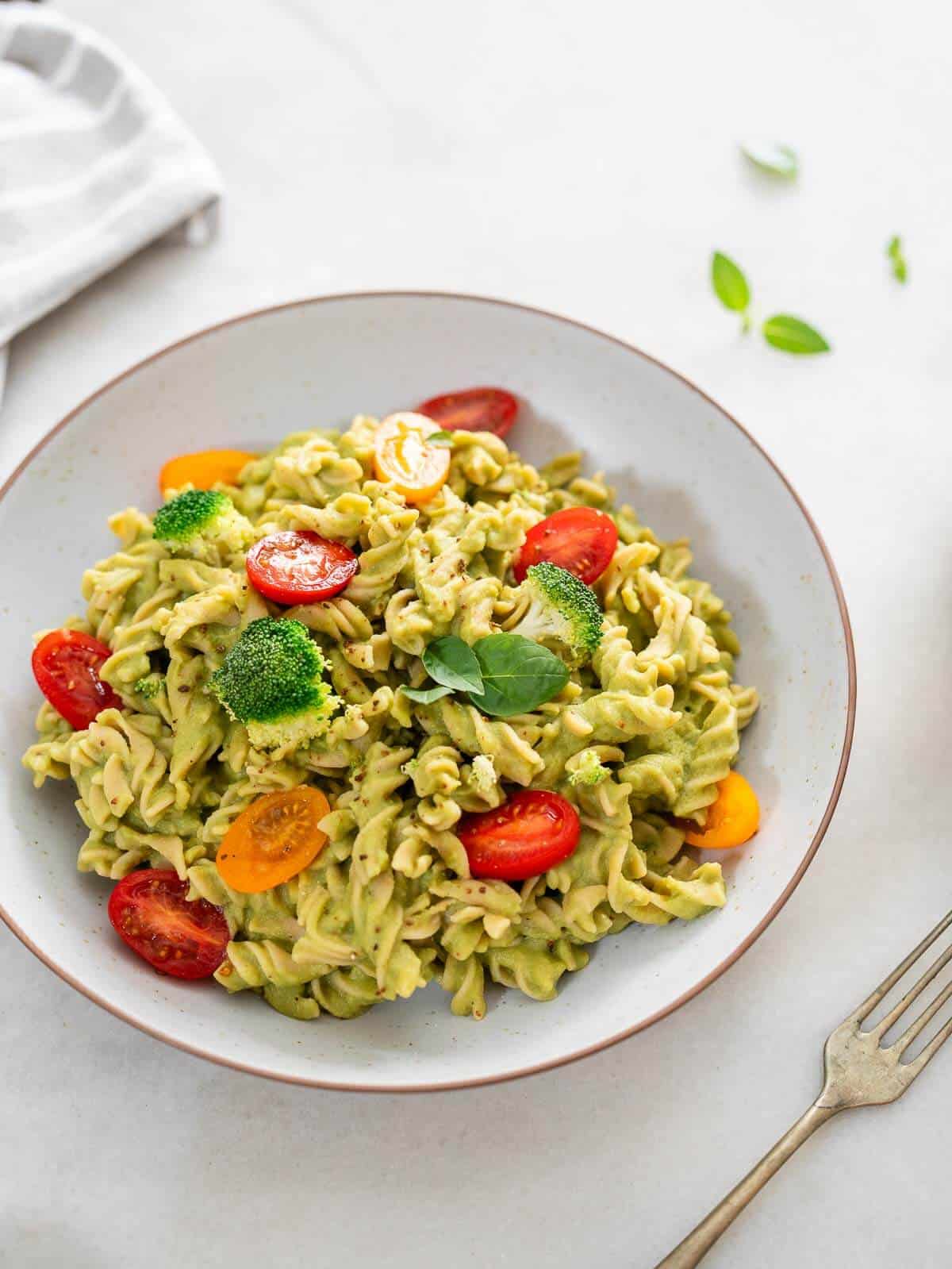 plato servido con pasta con brócoli cremosa junto a un tenedor.