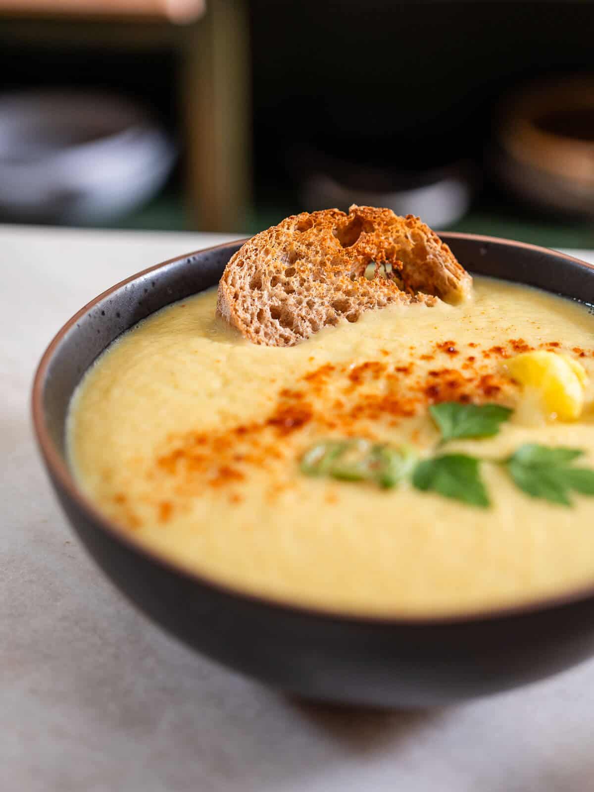 sopa de coliflor servida con pan italiano artesanal tostado.