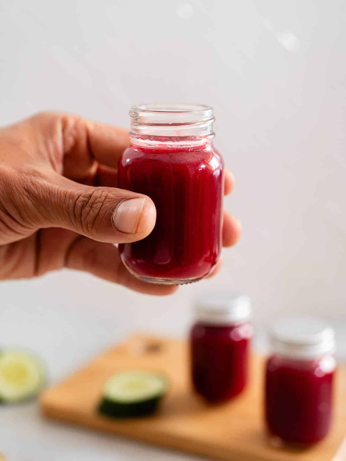 mano sosteniendo un pequeño vaso con jugo para desinflamar el estómago.