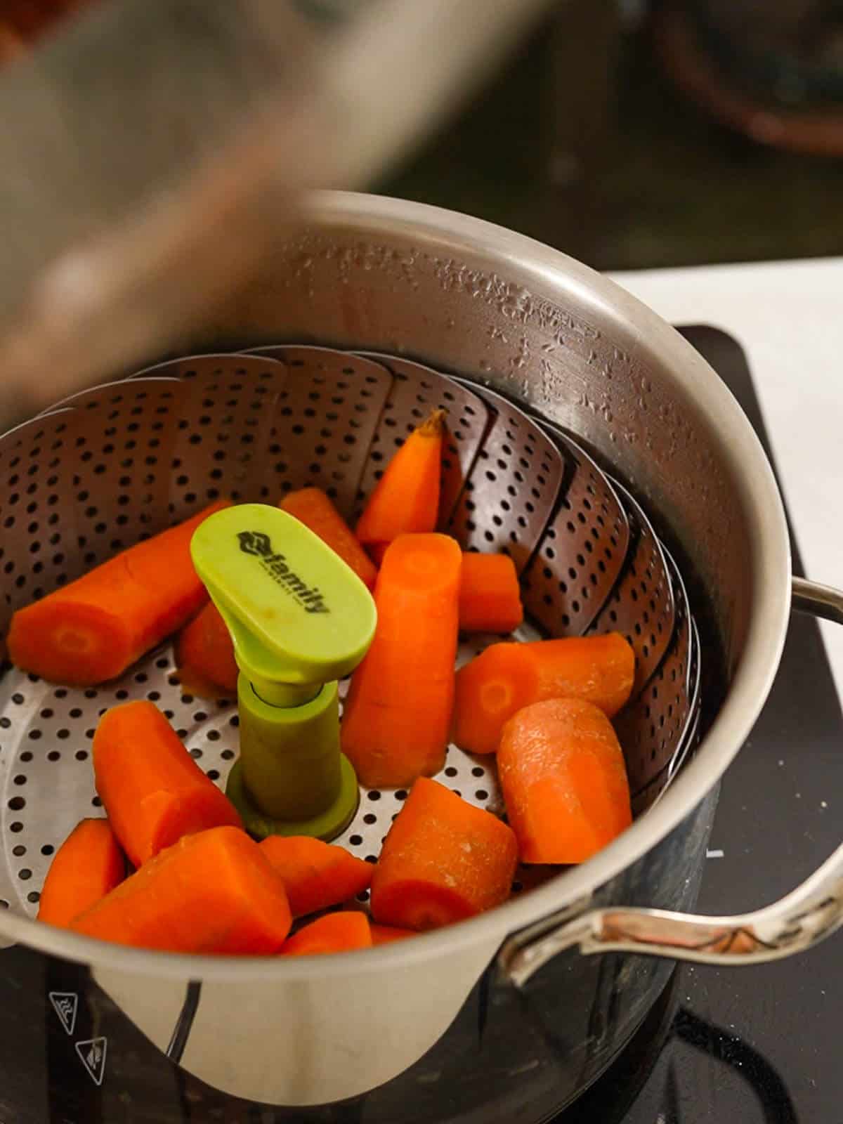 Cocer al vapor zanahorias picadas en una olla al vapor.