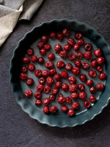 Molde para tarta con cerezas congeladas distribuidas en una sola capa.