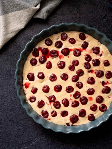 Molde para tarta con cerezas congeladas distribuidas en una segunda capa.