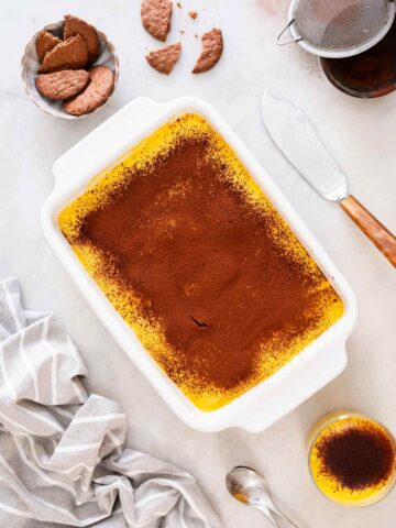 Vista superior de la tarta en una fuente rectangular, con polvo de cacao lista para servir.