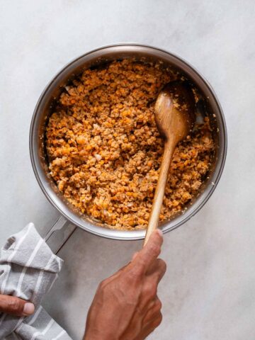 Ingredientes para las albóndigas, como la soja texturizada, lentejas rojas y cebolla, combinados en una sartén metálica.