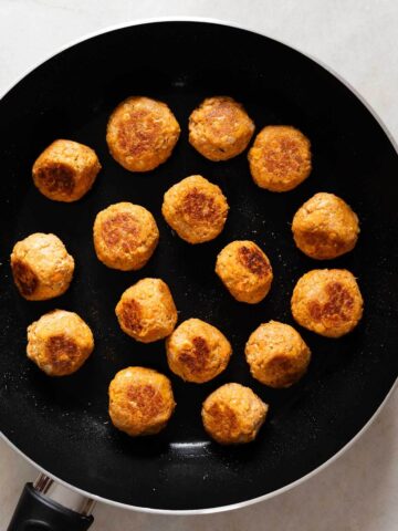 Albóndigas veganas cocinadas, mostrando un dorado uniforme en una sartén negra.