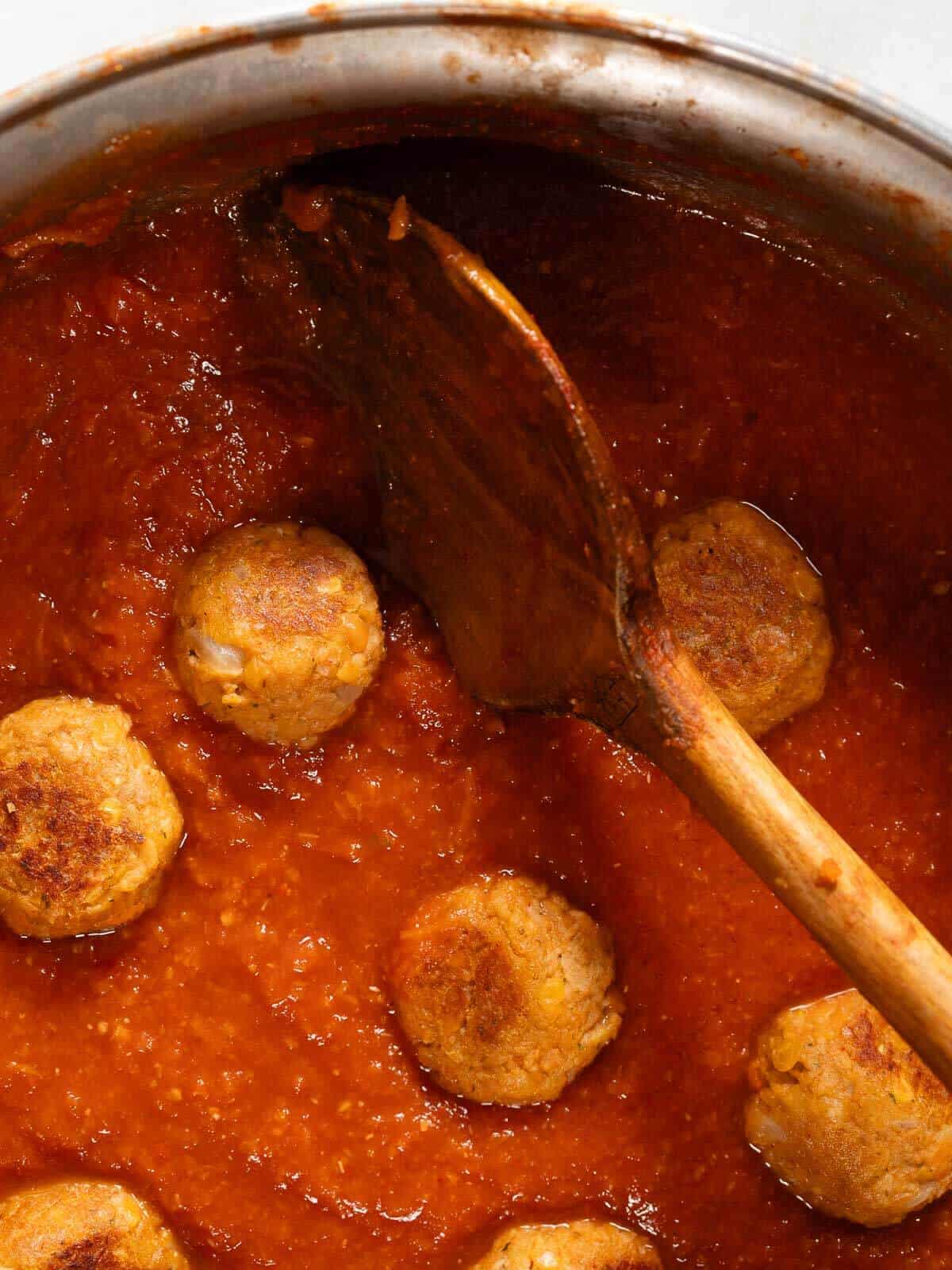 Albóndigas dorándose en una sartén con salsa marinara.