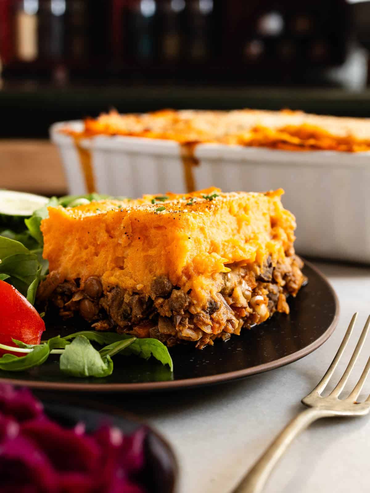 porción de pastel de papa vegetariano servido con ensalada verde y tomate.