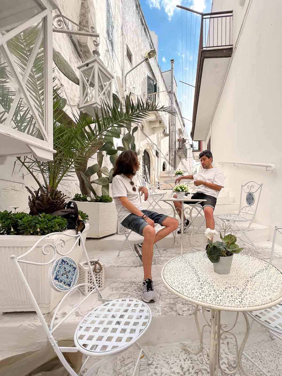 dos personas tomando un café en una escalinata empedrada.