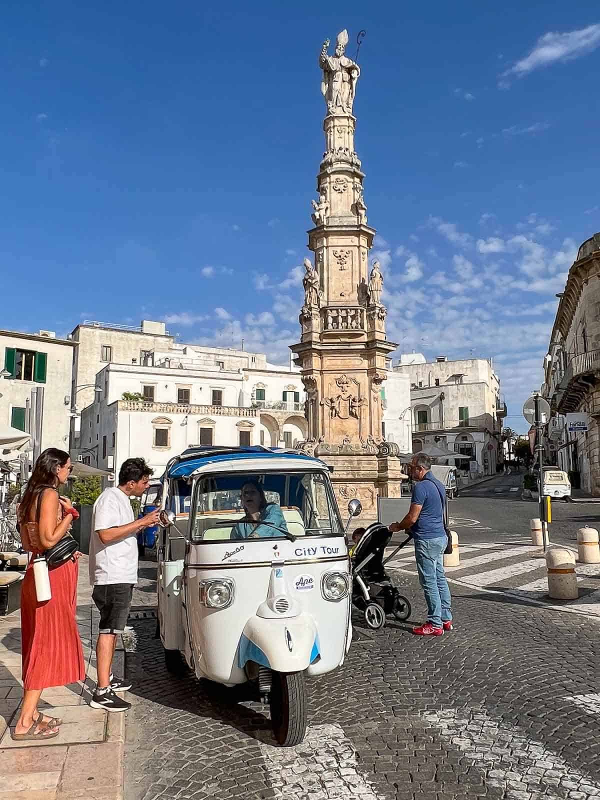 personas a punto de tomar un Tuc Tuc en el centro de Ostuni.