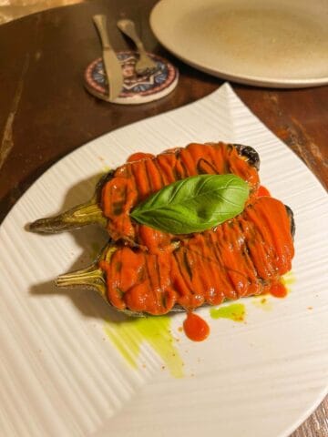 plato de berenjenas rellenas con salsa de tomate y hoja de albahaca.