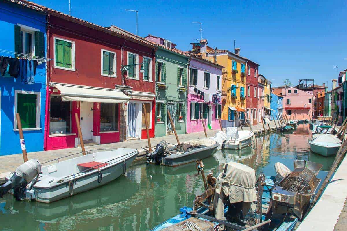 Canal en Murano con barcos y edificios - Canal en Murano con barcos atracados y edificios históricos.