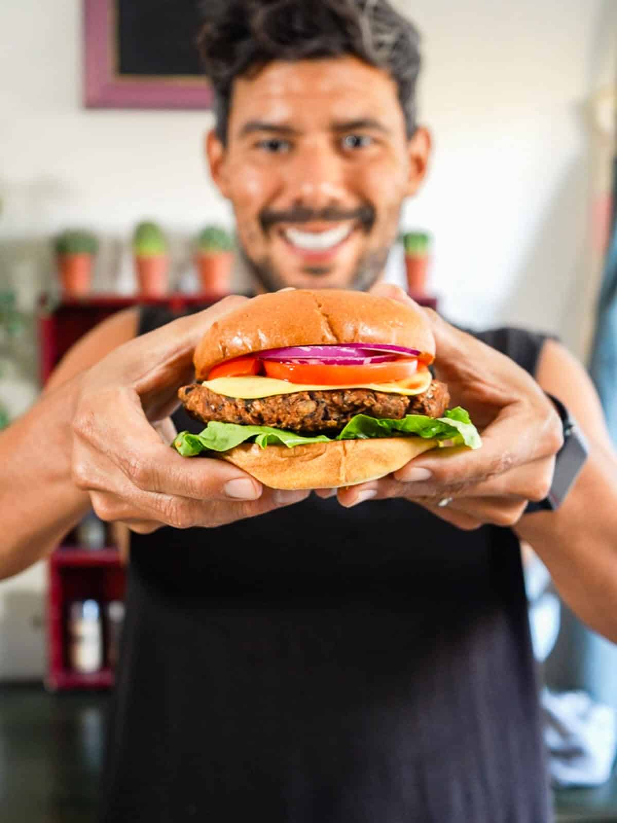 hombre enseñando una hamburguesa de frijoles armada.