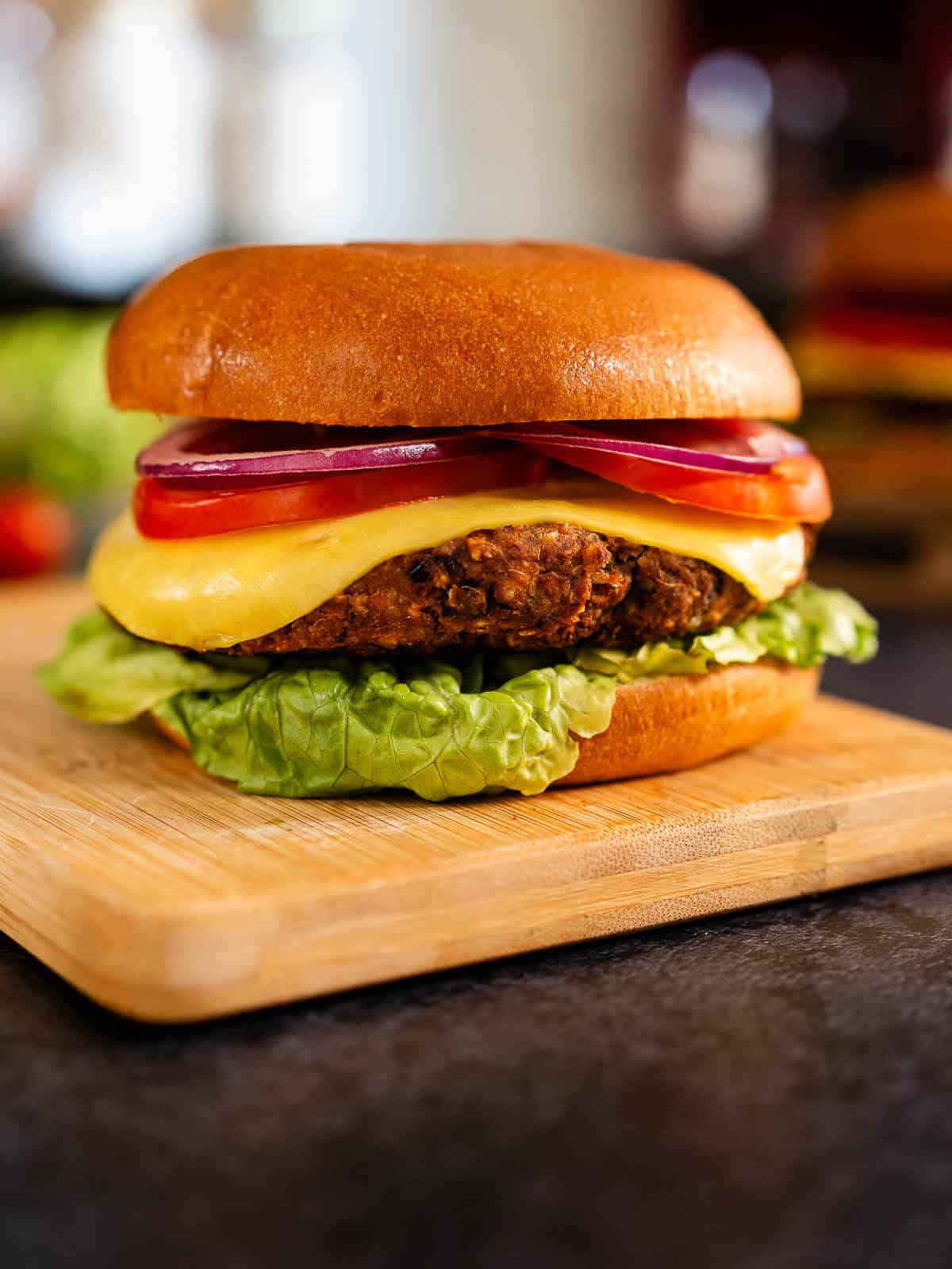 Hamburguesa de frijoles negros servida en un pan con lechuga, tomate, cebolla y queso vegano.