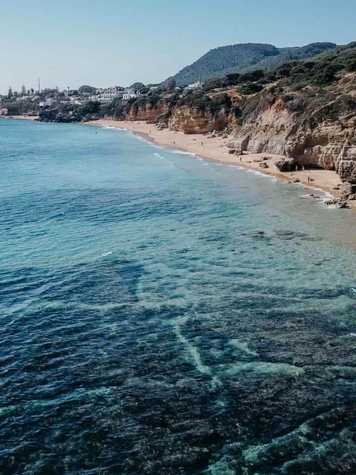 Vista aérea de Caños de Meca, destacando su impresionante entorno natural con dramáticos acantilados y aguas claras y azules.