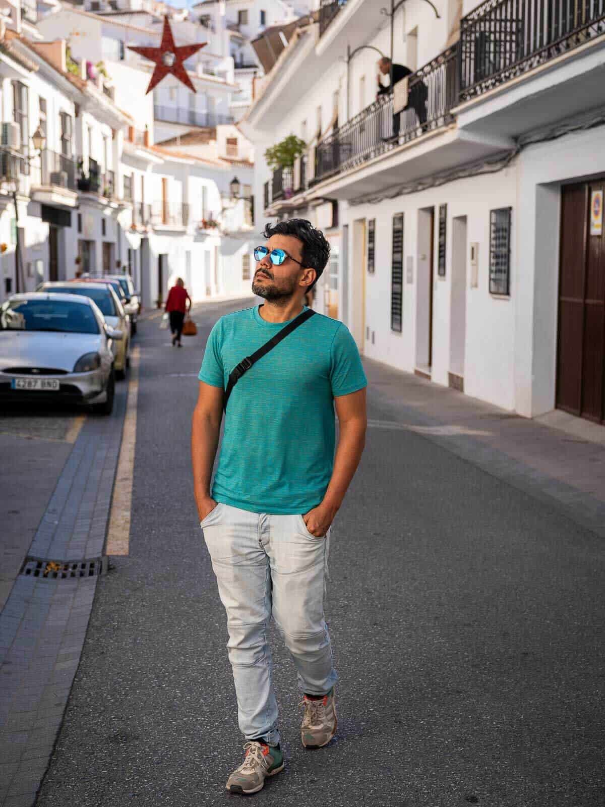 Hombre caminando por una calle en Frigiliana, rodeado de casas blancas y ambiente tranquilo.