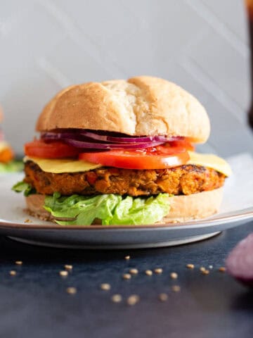 Hamburguesa de lentejas y avena estilo gourmet – Primer plano de una hamburguesa vegana con toppings frescos y pan, ideal para una comida plant-based.