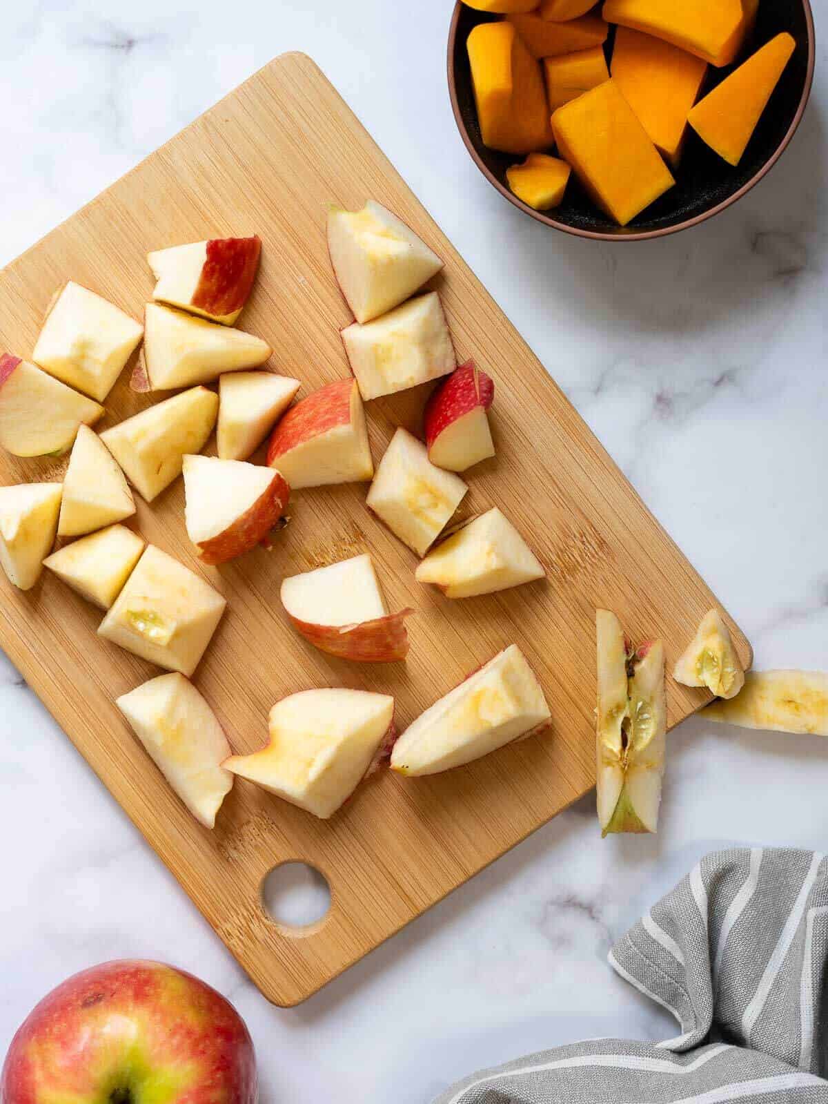 Preparación de jugo de calabaza con manzana fresca: trozos de manzana cortados en una tabla de madera, listos para ser procesados. Ingredientes de calidad para una experiencia de sabor única.