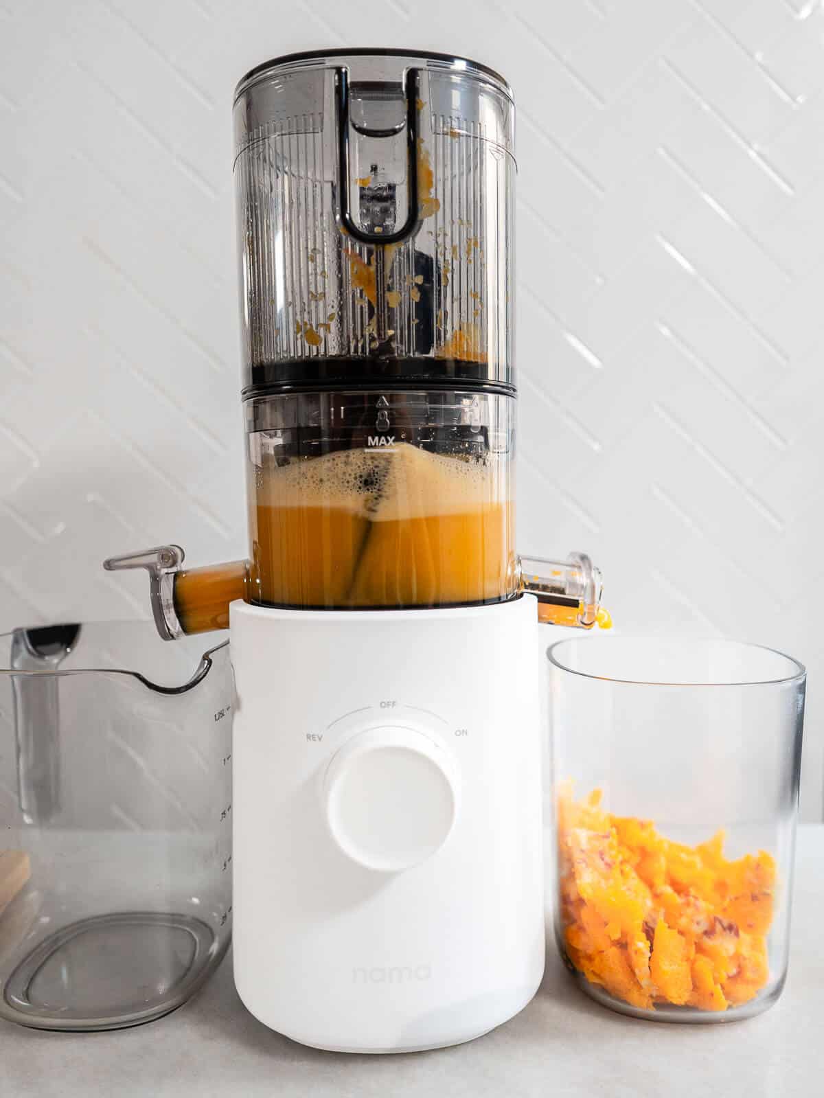 Extractor de jugos de alta calidad separando la pulpa mientras produce un jugo de calabaza y manzana vibrante. Ideal para amantes de las bebidas naturales y frescas.