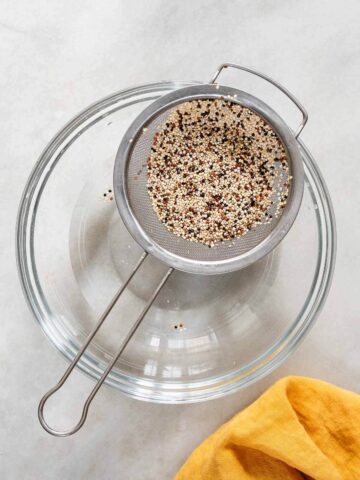 lavando la quinoa con un colador sobre un bol con agua.