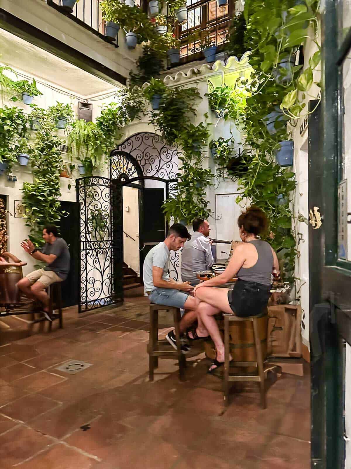 Tapas en El Pimpi: Interior del restaurante El Pimpi con un ambiente típico andaluz lleno de flores y decoración tradicional.