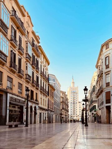 Calle Larios, Málaga: Calle peatonal con piso de mármol y una concurrida actividad comercial y cultural.