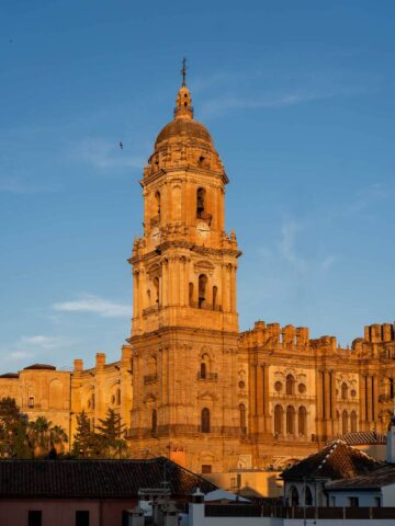 Catedral de Málaga al atardecer: La fachada iluminada por los últimos rayos del sol, resaltando su arquitectura histórica.