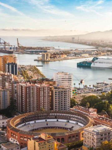 Playa y centro histórico de Málaga: Vista panorámica del puerto de Málaga con la plaza de toros y la catedral al amanecer.